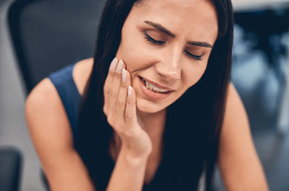 Mulher com mão na cara por causa da dor de dentes Mulher com mão na cara por causa da dor de dentes