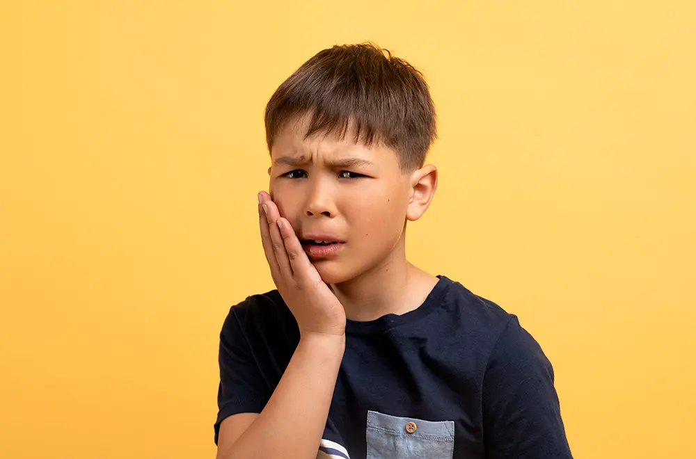 Criança com a mão na cara com dor de dentes Criança com a mão na cara com dor de dentes
