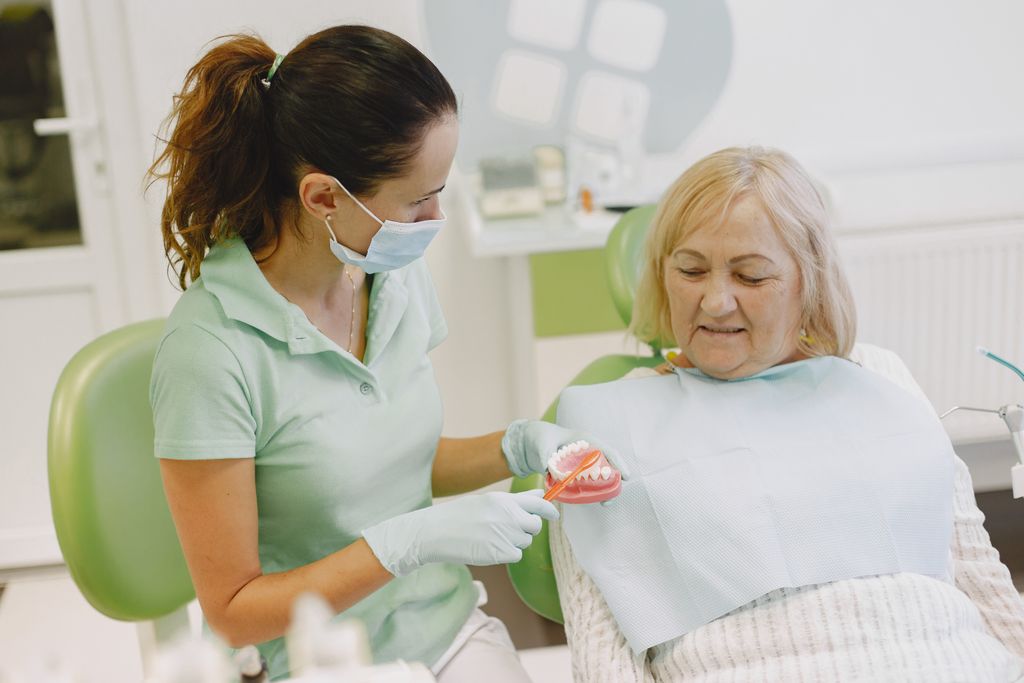 Dentista a explicar cuidados com a prótese dentária a uma paciente sénior