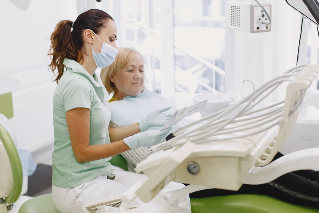 Dentista a rever opções de tratamento com paciente sénior em consulta