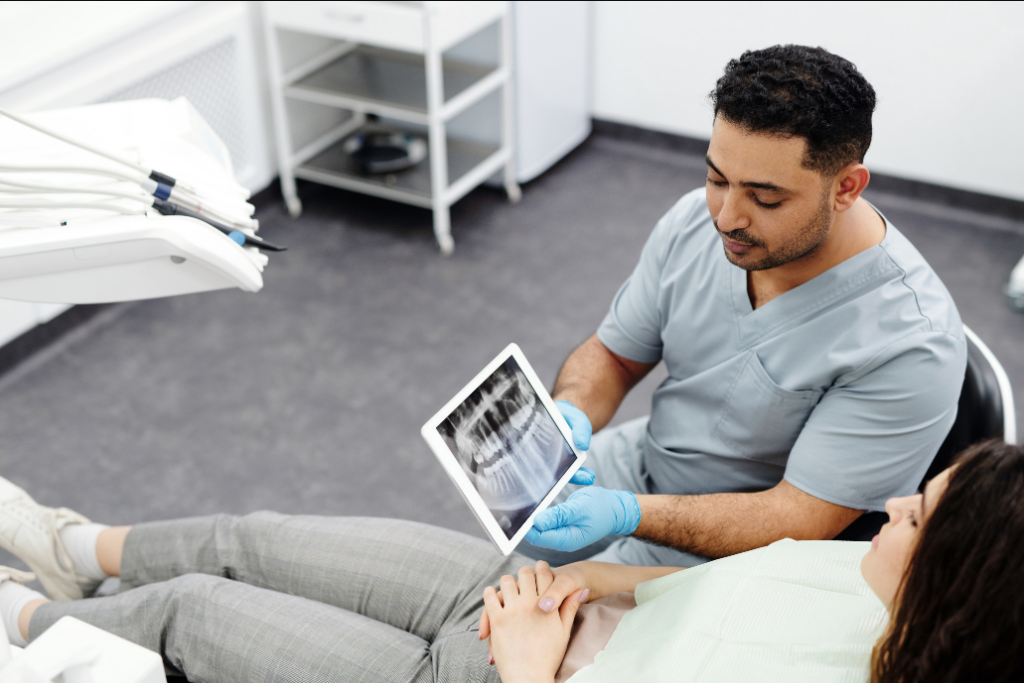 Médico dentista a explicar uma radiografia dentária a uma paciente
